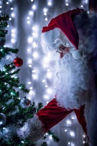 Santa Looking At Holiday Lights On Tree