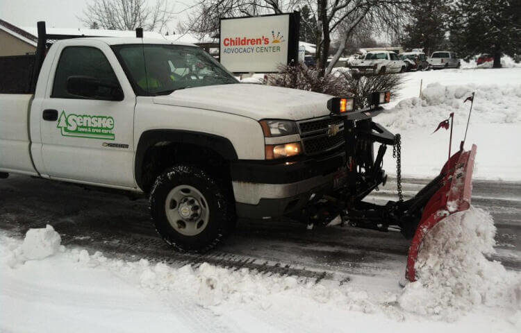 truck plowing snow in parking lot